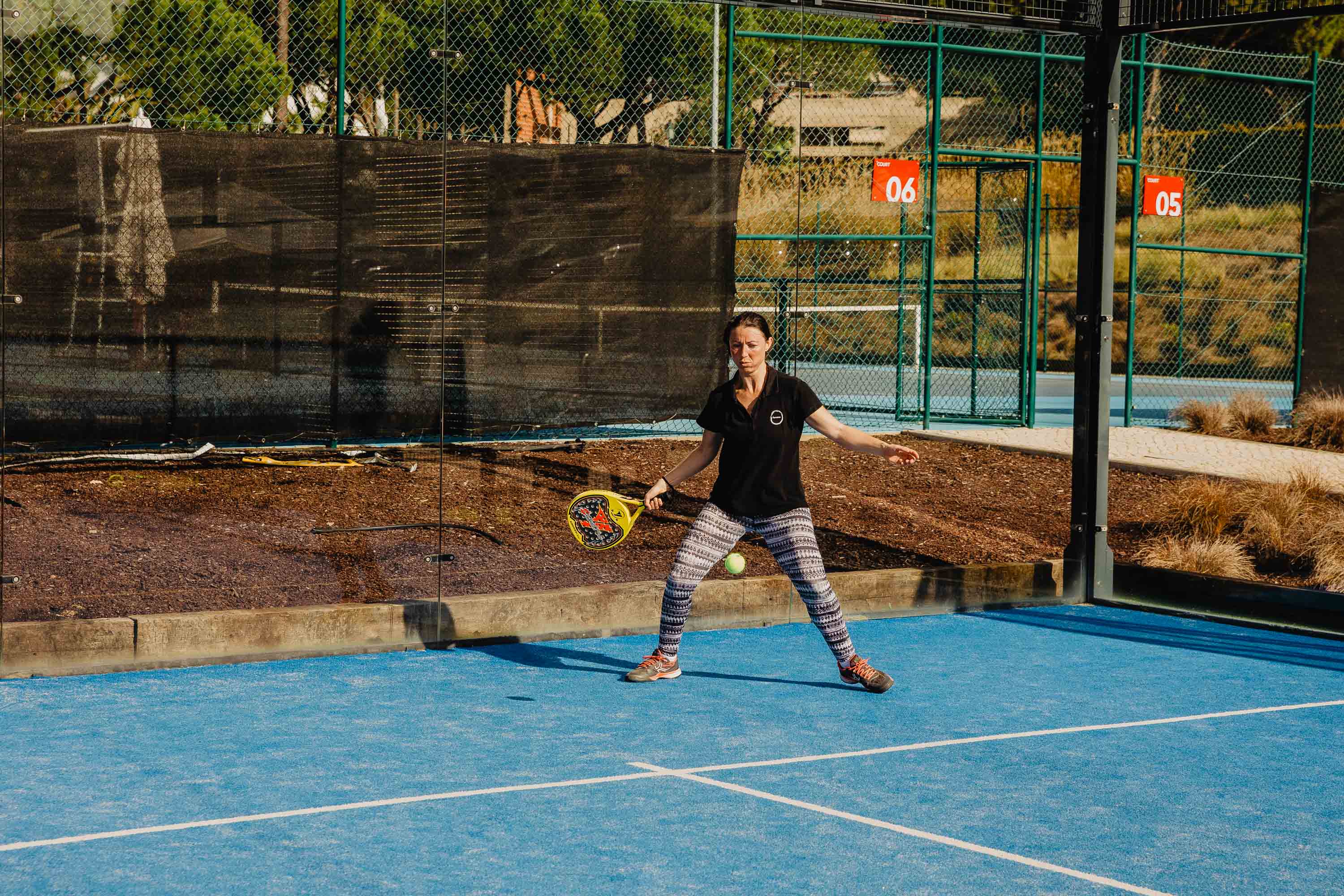 Woman playing padel on the court at The Campus, in action in an outdoor sports setting.